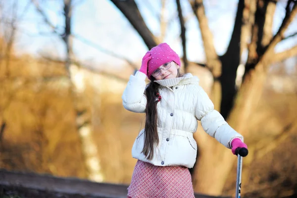 Malá dívka, která nosí růžové čepici s skútr — Stock fotografie