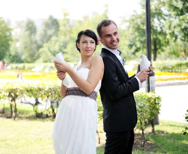 Bruden och brudgummen med duvor på bröllop walk — Stockfoto