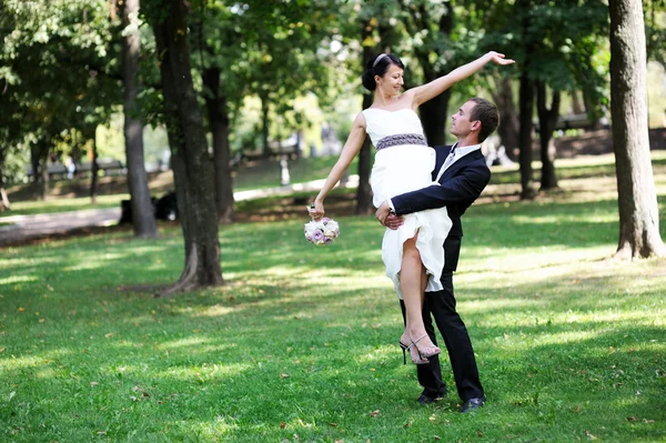 Gelukkige bruidegom met bruid in zijn armen — Stockfoto