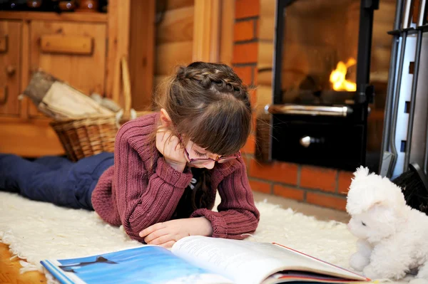 Dítě dívka čte před krb — Stock fotografie