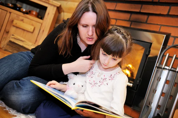 Mother and daughter reading in front of fireplace — Stock Photo, Image