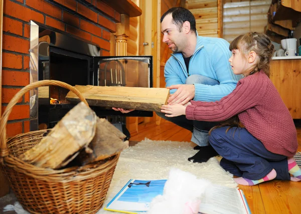 Pai e filha colocando madeira em lareira Fotografias De Stock Royalty-Free