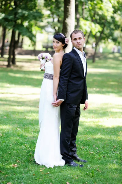 Bruden och brudgummen poserar utomhus på bröllopsdagen — Stockfoto