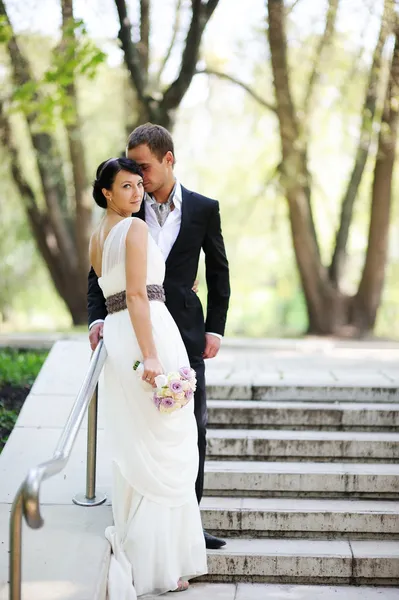 Bruden och brudgummen poserar utomhus på bröllopsdagen — Stockfoto
