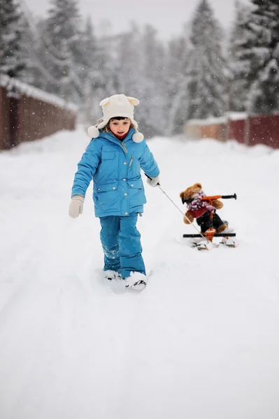 小さな女の子がおもちゃで彼女の雪のスクーターを引いてください。 — ストック写真
