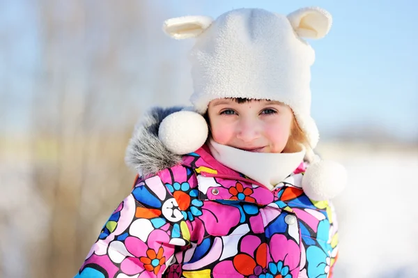 Batole dívka v barevné kombinézu hraje ve sněhu — Stock fotografie