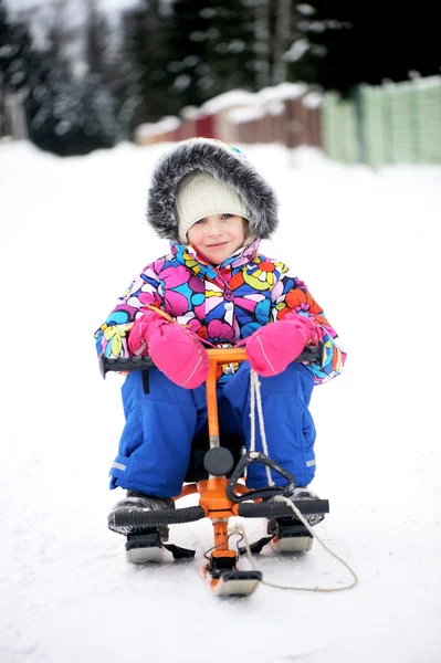 Barn girl ridning hennes snöskoter — Stockfoto