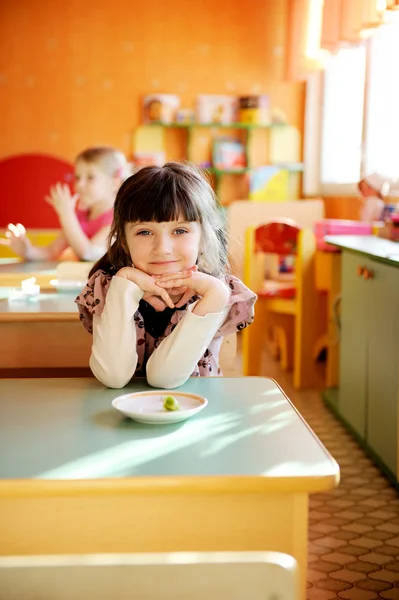 Gelukkig meisje zitten aan een tafel — Stockfoto