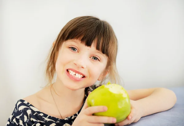 Счастливая девочка ест яблоко дома — стоковое фото