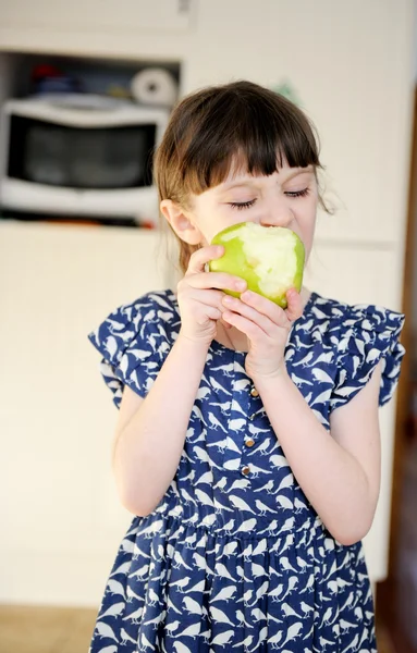 Чарівна дівчинка їсть яблуко вдома — стокове фото