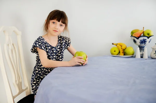 Kind meisje met een appel in keuken — Stockfoto
