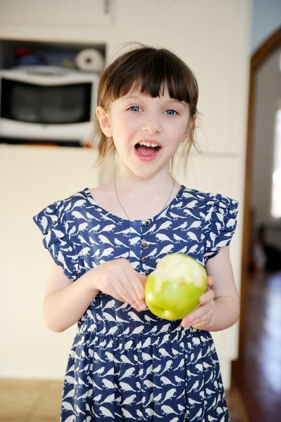 Lyckligt barn flicka äta äpple hemma — Stockfoto
