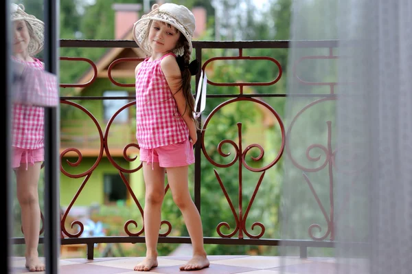 Fancy barn flicka i solhatt poserar på balkong — Stockfoto