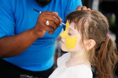 Cute little girl has her face painted clipart