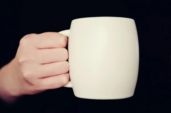 Hand with white cup isolated on black background — Stock Photo, Image