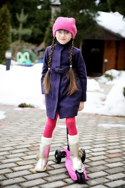 Barn flicka Rider hennes skoter längs vägen — Stockfoto