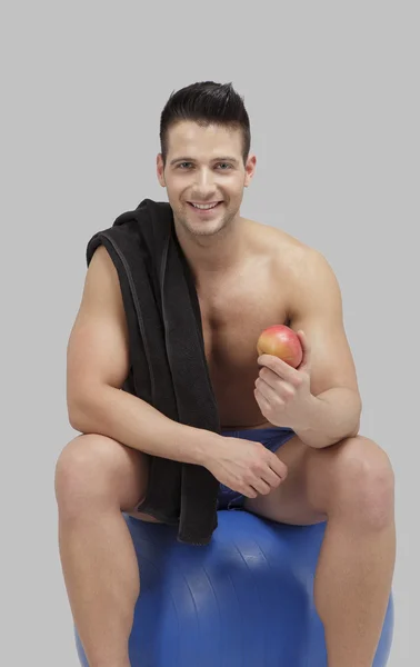Fitness topu üzerinde oturan genç yetişkin erkek — Stok fotoğraf