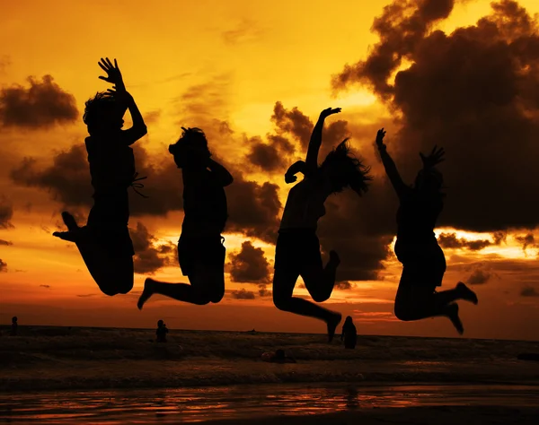 Silhueta de amigos pulando ao pôr do sol — Fotografia de Stock