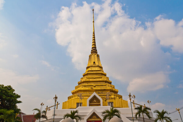 Golden pagoda with trees and clouds around the sky as a backdrop