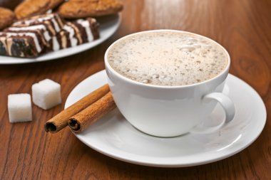 Cappuccino with cinnamon bark and sweets clipart