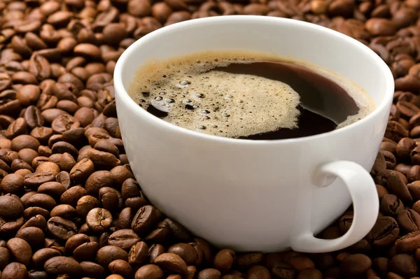 Taza de café en un montón de granos de café — Foto de Stock