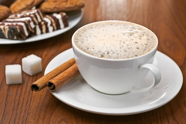 Cappuccino with cinnamon bark and sweets — Stock Photo, Image