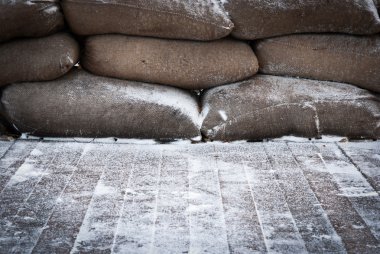 Old brown sandbags on snow covered wooden floor clipart