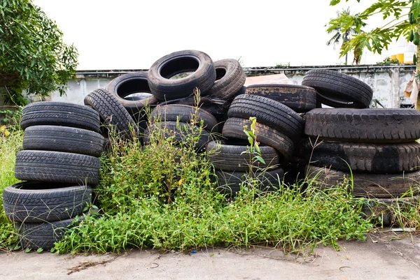 Old road tires stacked on grass land — Stock Photo, Image