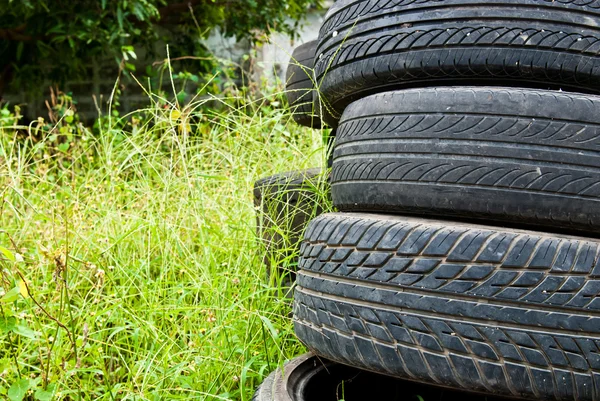 Old road tires stacked on grass land — Stock Photo, Image