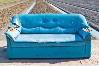 Very old vintage blue sofa on the street clipart
