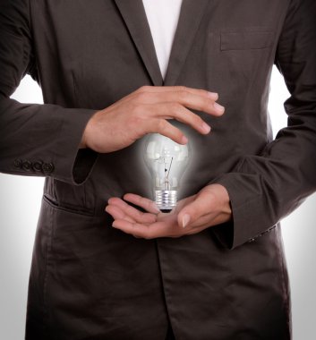 Business man holding light bulb in his hand clipart