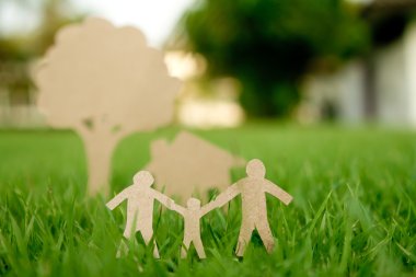 Paper cut of family with house and tree on fresh spring green gr