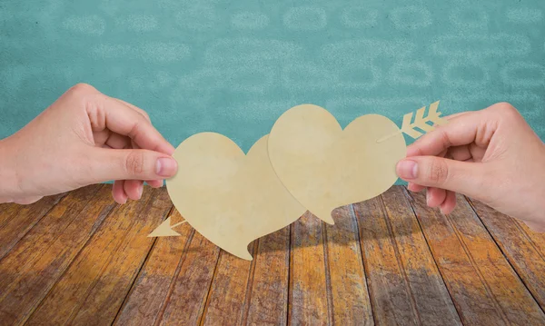 Handen met twee papier hart en pijl — Stockfoto