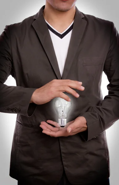 Бизнесмен держит в руке лампочку. — стоковое фото