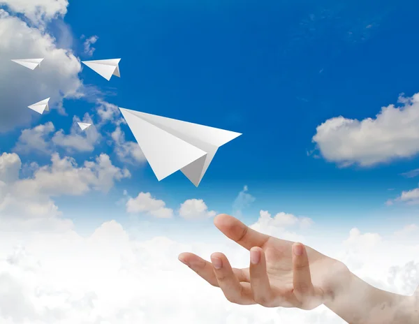 Ruka házet papírové letadlo v oblacích — Stock fotografie