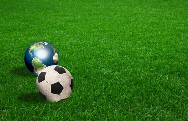 Bola de futebol e terra na grama verde — Fotografia de Stock