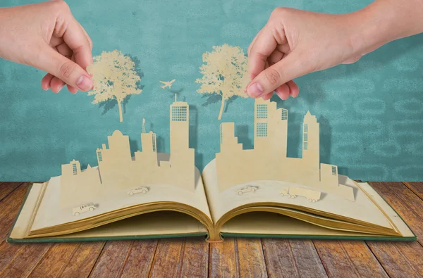 Ręka trzymać cięcia papieru drzewa nad papieru wyciąć miast z samochodu — Zdjęcie stockowe
