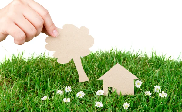 Main tenir le papier coupé de la maison sur l'herbe verte de printemps frais — Photo