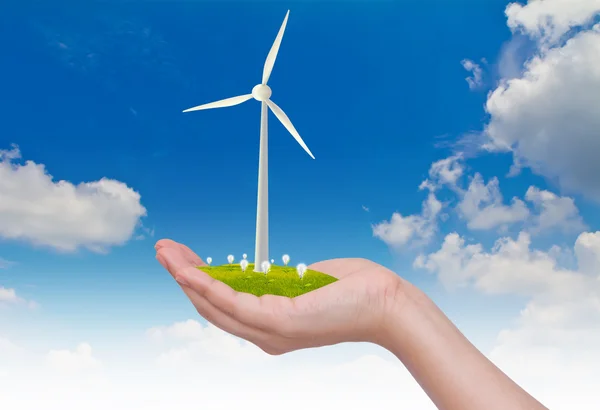 Turbinas eólicas y bombilla en la mano sobre el cielo azul — Foto de Stock