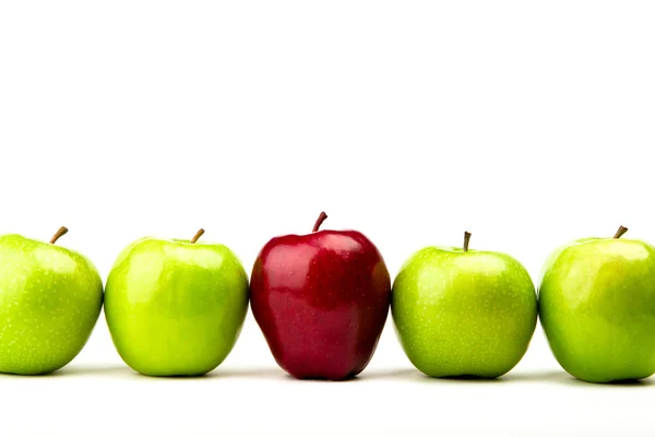 Červené jablko mezi zelenými jablky izolovaných na bílém — Stock fotografie