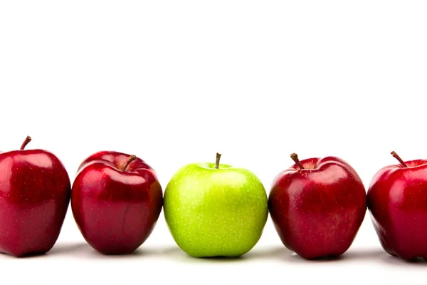 Zelené jablko mezi červená jablka izolovaných na bílém — Stock fotografie