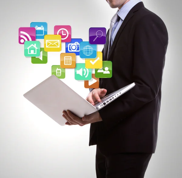 Homem de negócios com laptop e ícones de aplicação coloridos — Fotografia de Stock