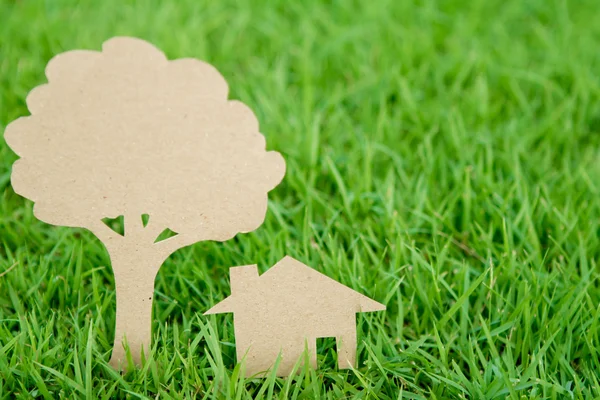 Χαρτί κομμένα από το σπίτι και το δέντρο σε ανοιξιάτικα πράσινο χορτάρι — Φωτογραφία Αρχείου