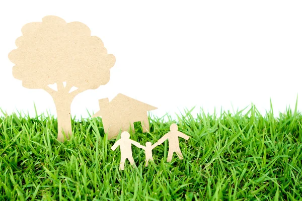 Вырезанная из бумаги семья с домом и деревом на свежей весенней зеленой гр. — стоковое фото
