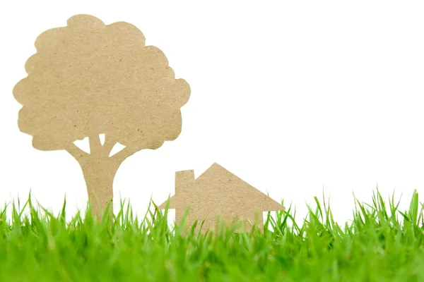 Corte de papel de casa e árvore na grama verde fresca da primavera — Fotografia de Stock