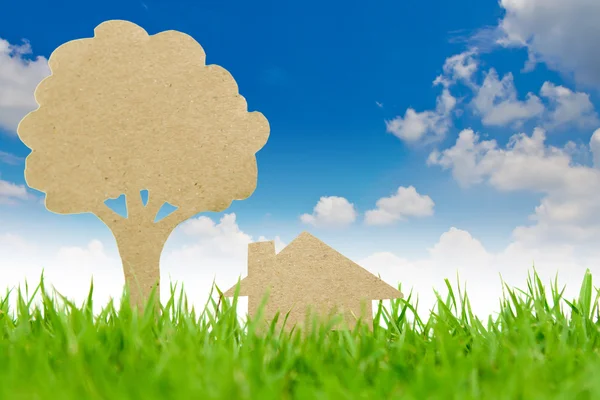 Cięcia papieru dom i drzewa na świeże wiosenne zielone trawy — Zdjęcie stockowe