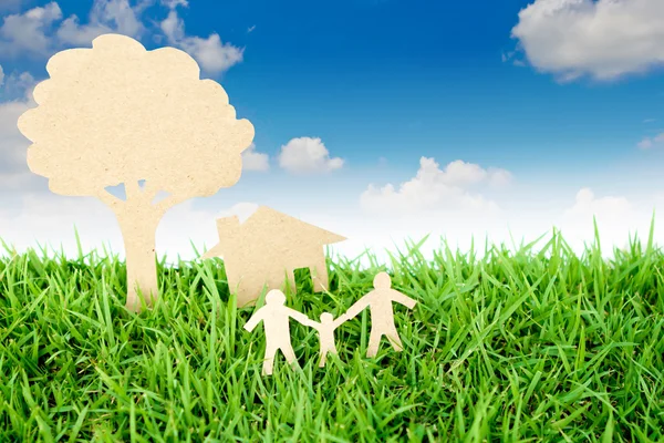 Вырезанная из бумаги семья с домом и деревом на свежей весенней зеленой гр. — стоковое фото