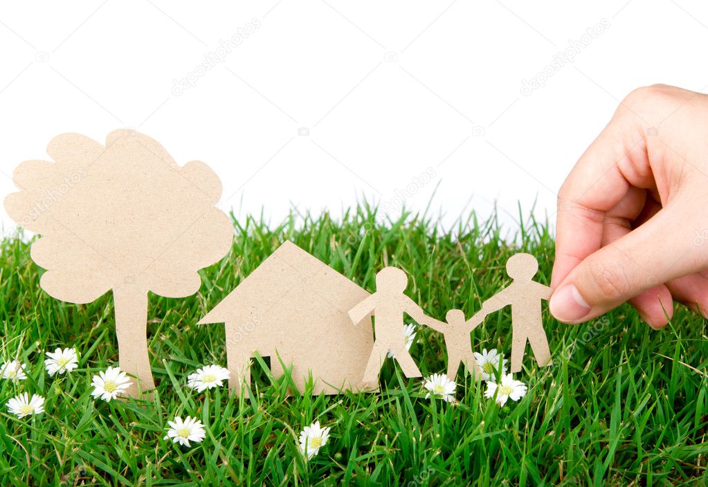 Hand hold paper cut of family over fresh spring green grass