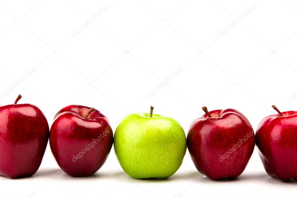 Green apple among red apples isolated on a white