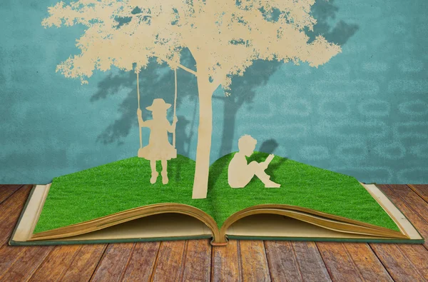 A redução de papel de crianças lê um livro e crianças no balanço abaixo do tr — Fotografia de Stock